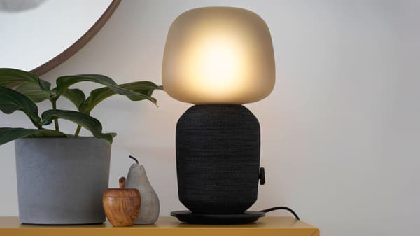 Lampa s reproduktorem Symfonisk, vedle ní jsou dekorace a květináč s květinou
