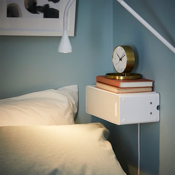 Lampa z głośnikiem WiFi SYMFONISK pośród akcesoriów dekoracyjnych na szafce w jadalni.