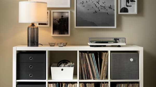 Lampada da tavolo TONVIS e giradischi su uno scaffale KALLAX bianco con dischi in vinile e vari contenitori.