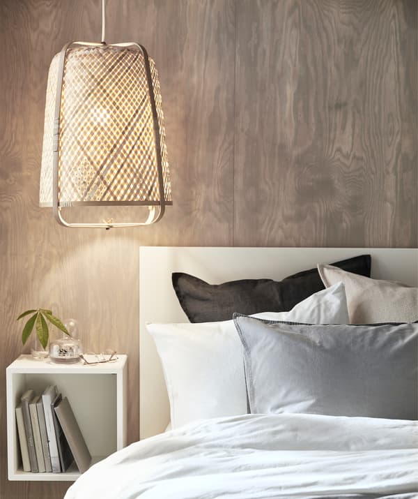 Lampada in bambù sopra un letto e uno scaffale da parete.