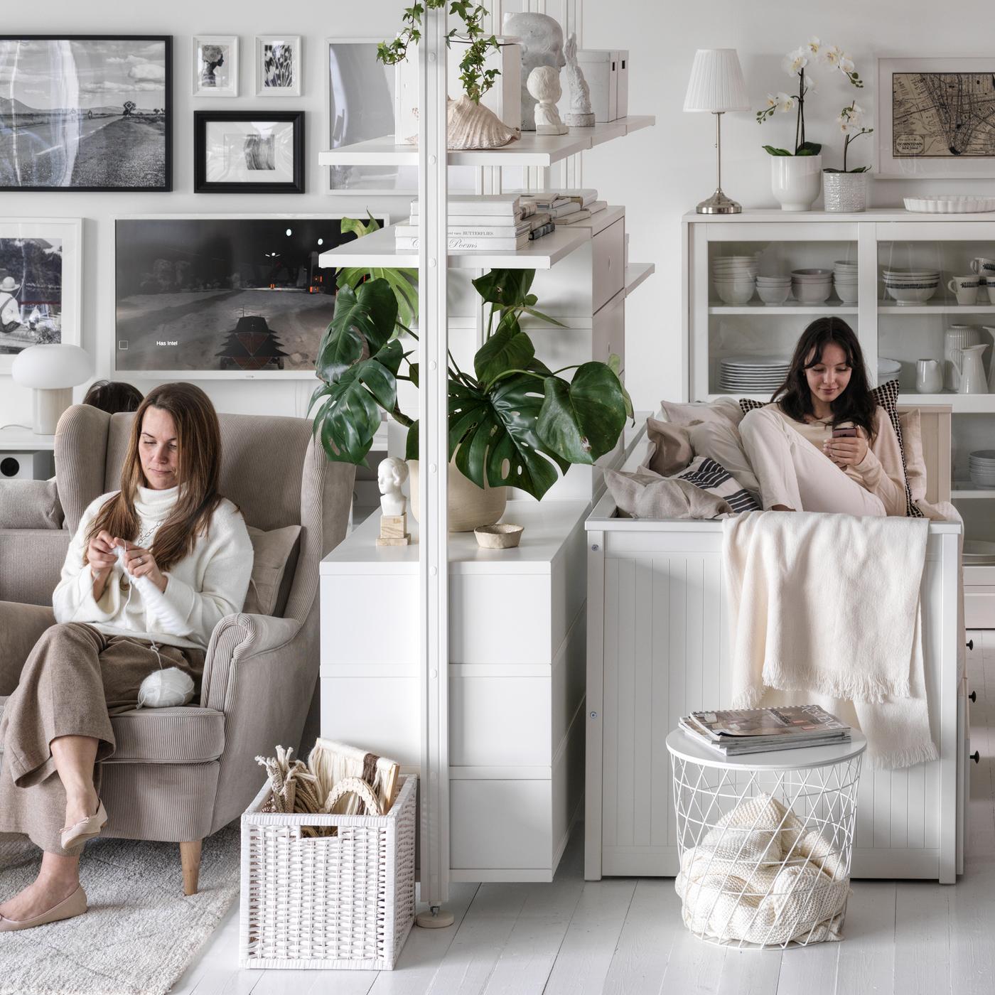 Lampadario STORSLINGA bianco e nero in una stanza luminosa con lampada da terra bianca NYMÅNE accanto a un divano bianco con cuscino - IKEA.