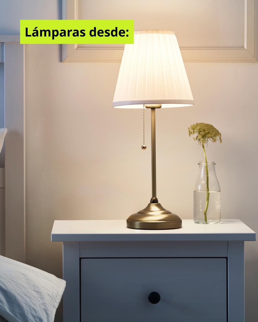 Lámpara de base dorada sobre velador blanco con llamado desde