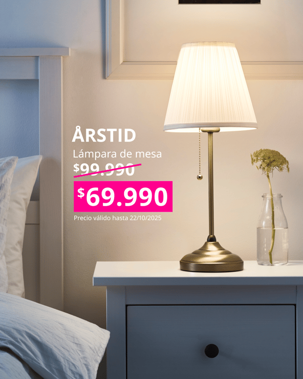 Lámpara de mesa ARSTID con pantalla blanca y base de metal en una mesita de noche blanca HEMNES.