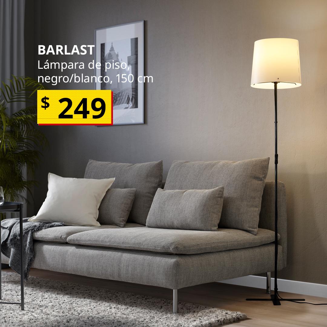 Lámpara de piso BARLAST en color negro y blanco junto a un sofá gris en una sala de estar.