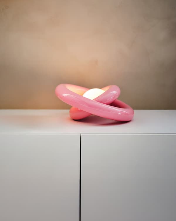 lámpara rosada encendidasobre una mesa blanca.
