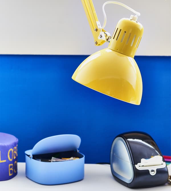 Lampe de bureau jaune sur fond de mur bleu.