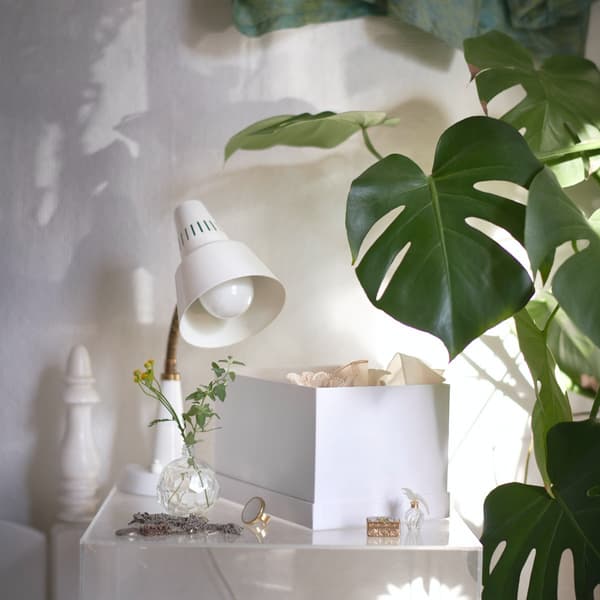 Lampe de chevet blanche sur une commode à côté d'une plante verte