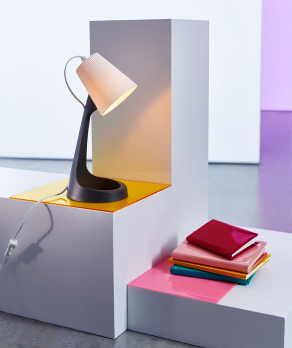 Lampe de table en plastique sur socle au-dessus d'une pile de livres.