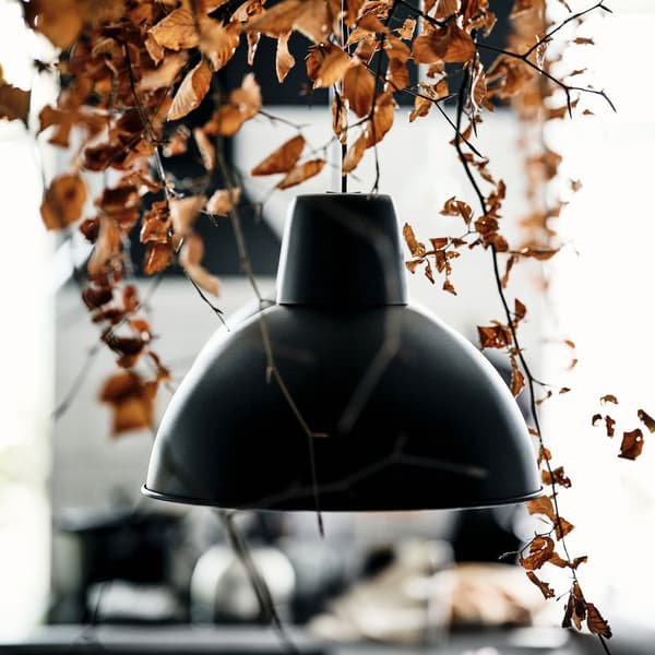Lampe SKURUP noire avec des feuilles en arrière plan 