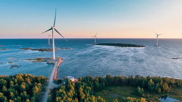 Landschaft mit grünen Bäumen,Wasser, einer durchgehenden Straße und Windkrafträder.