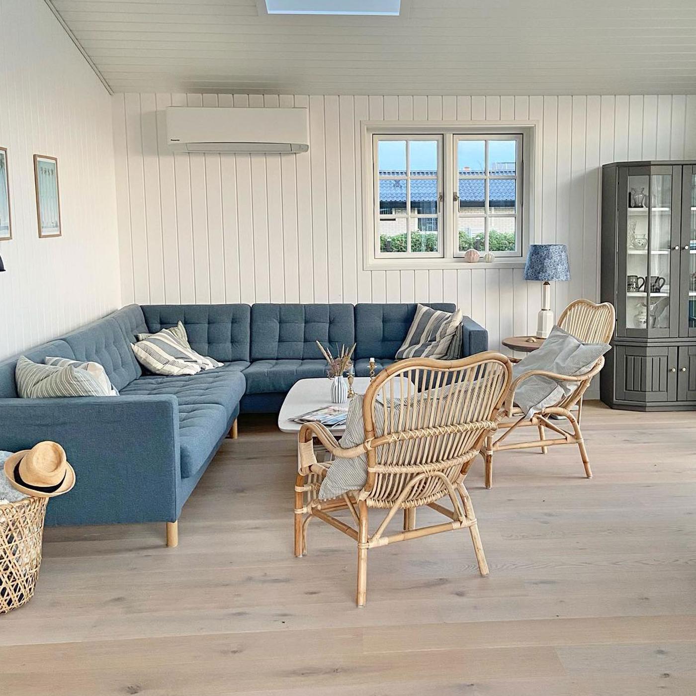 LANDSKRONA hörnsoffa i stort vardagsrum med vit träpanel på väggarna. 