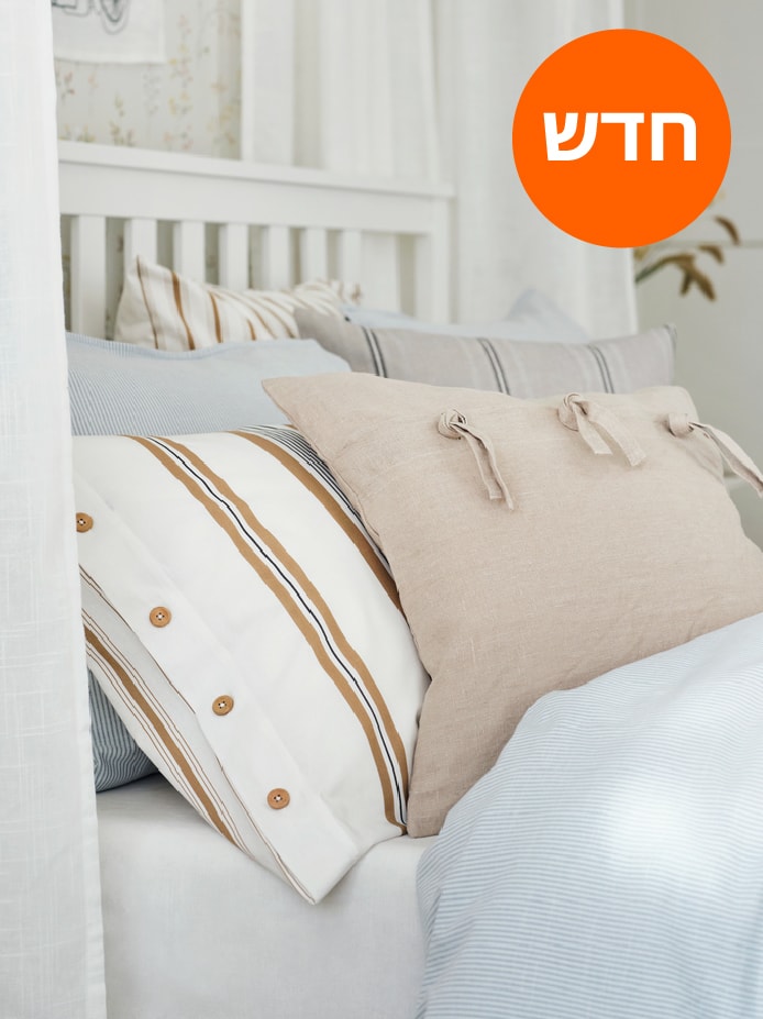 כרית בתוך ציפית LAPPDUNÖRT מפוספסת וכרית בכיסוי כרית AINA בצבע בז' נשענות כנגד כריות שינה אחרות על מיטה.