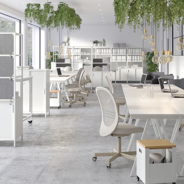 Large, airy office space with white TROTTEN storage units on castors, and desks, chairs and shelving units in light shades.