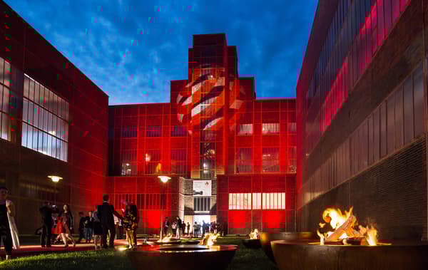 Large building lit with red lights and Red Dot Awards logo.
