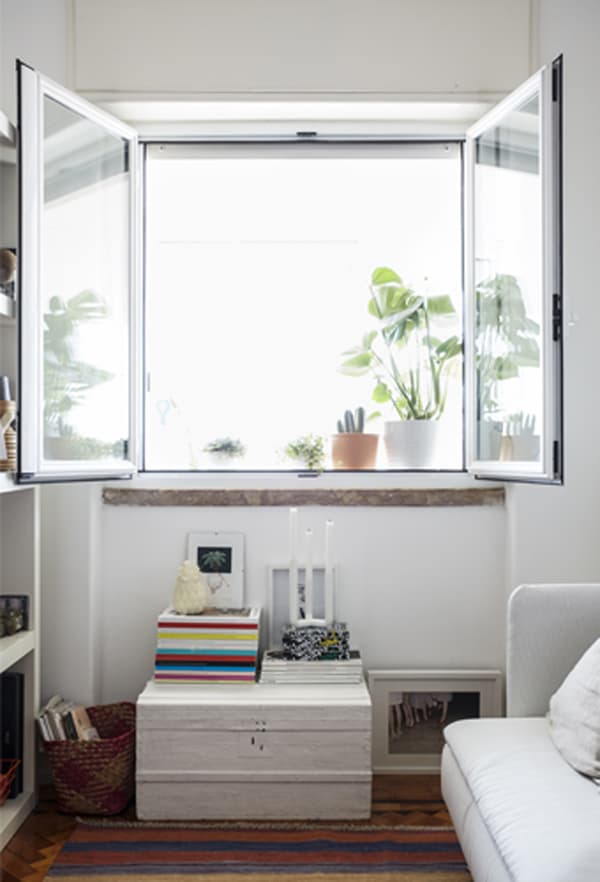 Large windows open in a white living room with striped rug.
