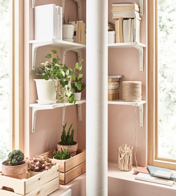 Las baldas EKBY ÖSTEN y los soportes EKBY STÖDIS blancos crean un almacenaje en esquina en un salón rosa.