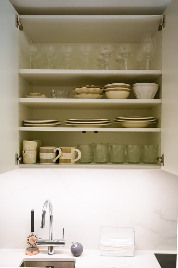 Lasit, lautaset, kupit ja kahvikupit on järjestelty siisteihin riveihin vaaleasävyisessä IKEA METOD -keittiössä.