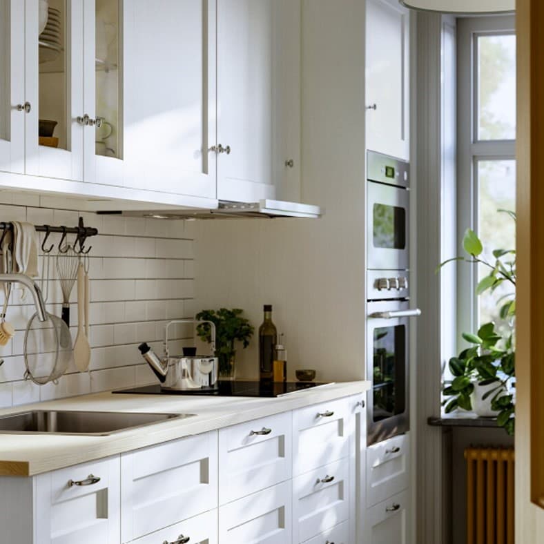 Lateral view of a kitchen with wall cabinets, base cabinets, doors and drawers in a white finish