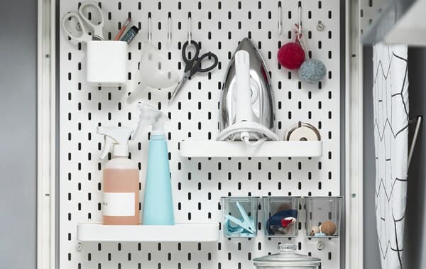 Laundry-related items stored on shelves, in pots and on hooks on a white pegboard.