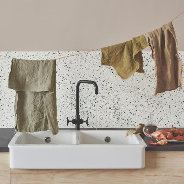 Lavello in ceramica HAVSEN su cui sono stesi alcuni strofinacci appesi ad un filo. Accanto, ci sono delle cipolle in un piatto.