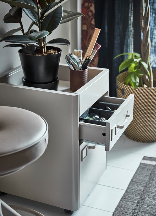 Le caisson à tiroirs IKEA IDÅSEN beige est muni de roulettes pour pouvoir le déplacer dans le bureau et créer un espace de travail flexible. La partie du haut possède un rangement ouvert dont les bords empêchent les objets de tomber.