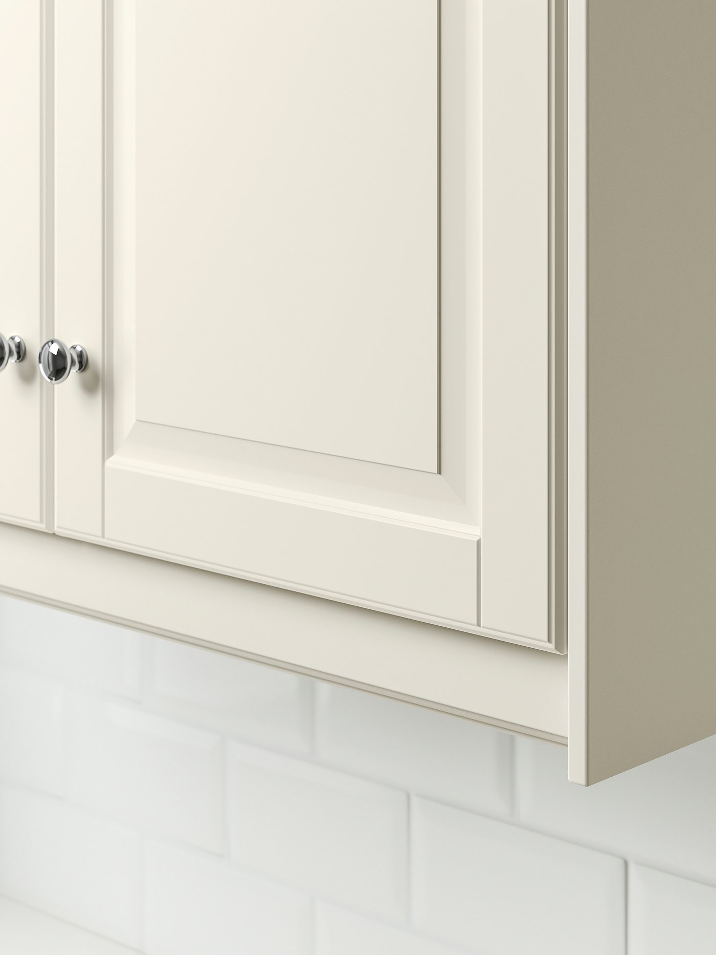 Le coin inférieur d’une armoire blanc cassé avec son bandeau-décor blanc cassé.