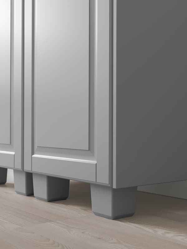 Le coin inférieur d’une armoire de cuisine grise avec des pieds gris assortis.