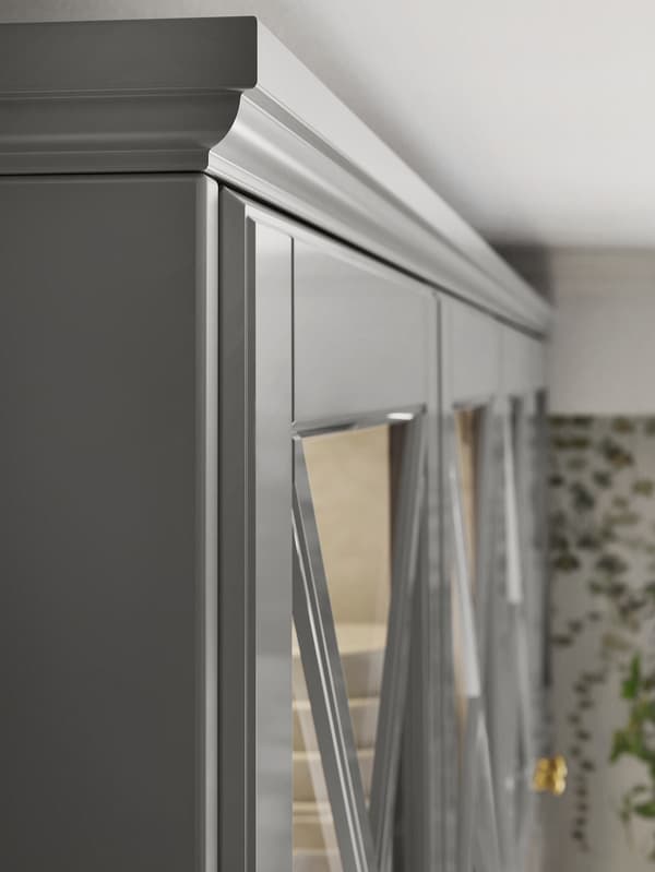 Le coin supérieur d’une rangée d’armoires de cuisine grises avec des portes vitrées et une moulure décorative profilée de la même couleur sur le dessus.