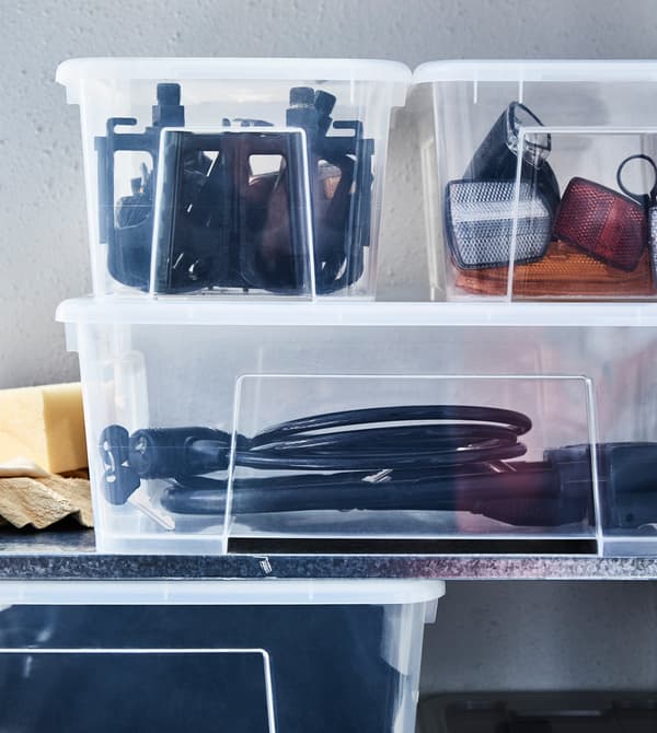Le matériel pour les activités de plein air et les accessoires de sport sont rangés sur une étagère, dans des boîtes en plastique transparent.