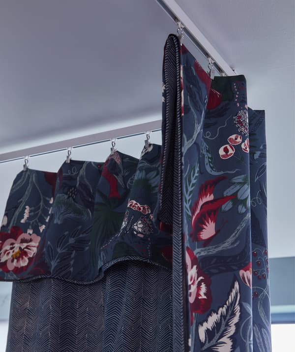 Le tissu IKEA FILODENDRON est bleu foncé avec un motif floral dans les tons bleu clair, blanc, rouge, rose et mauve.