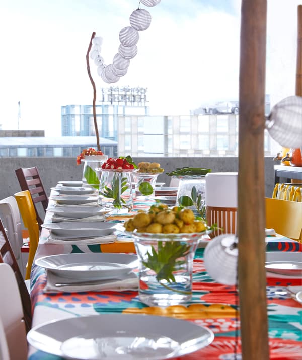 ไฟประดับ LED SOLARVET ของอิเกียมากับหลอดไฟพลังงานแสงอาทิตย์ 12 ดวงแขวนอยู่ที่โต๊ะงานเลี้ยงในแบฤดูร้อนที่เต็มไปด้วยสีสัน