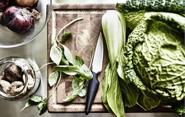 Légumes verts et feuilles de basilic sur une planche à découper en bois