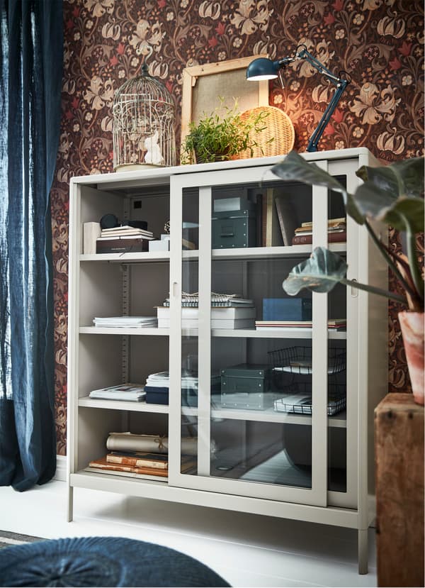 L’élément IKEA IDÅSEN beige à portes vitrées est suffisamment grand pour ranger le matériel d’un bureau à domicile, et assez compact pour s’intégrer aux petits espaces.
