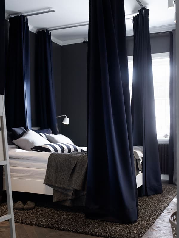 Les cortines pesades de color blau fosc a les cantonades d'aquest llit ajuden a esmorteir la llum i el so.