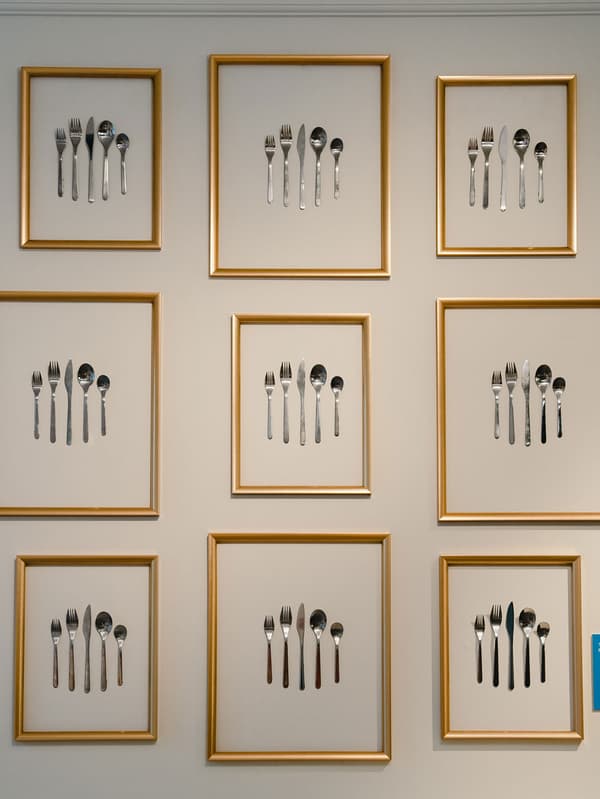 Les couverts tels que les cuillères, les fourchettes et les couteaux sont placés dans des cadres photo accrochés au mur.