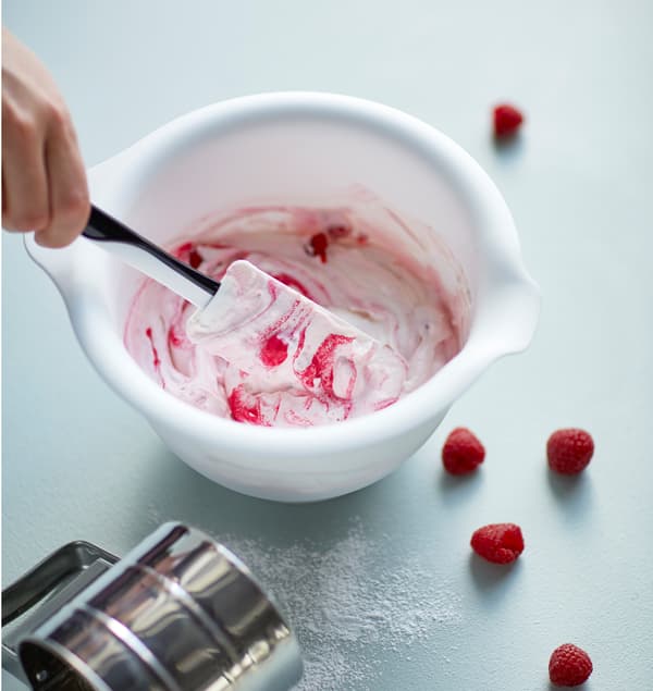 Les ingrédients pour un yourt à la framboise sont mélangés dans un saladier.