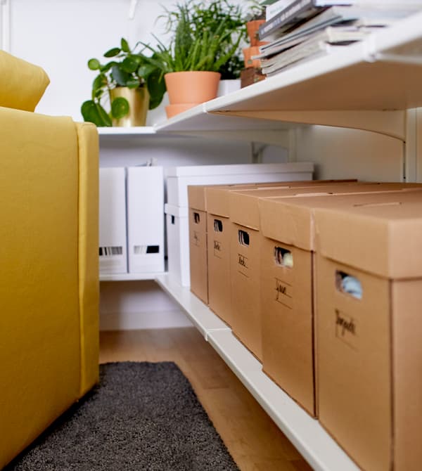 Les tablettes blanches peuvent accueillir un grand nombre de boîtes de rangement en papier, des magazines et des plantes en pot.