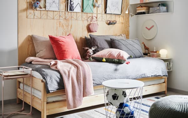 Letto impilabile UTÅKER con tanti cuscini e tessili, comodino, tavolino/contenitore, scaffale da parete e decorazioni.