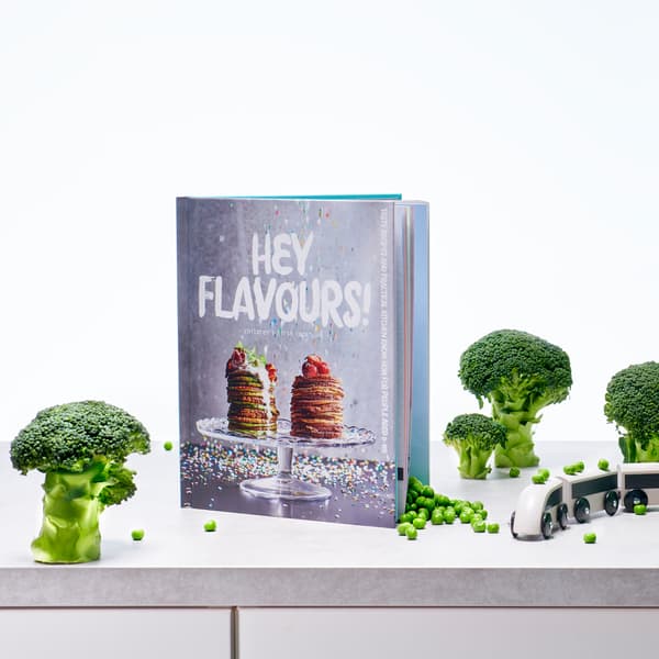 Libro MATVRÅ ¡Hola, sabores! con una portada que muestra tortitas apiladas con frutas del bosque por encima sobre un soporte para pastel.