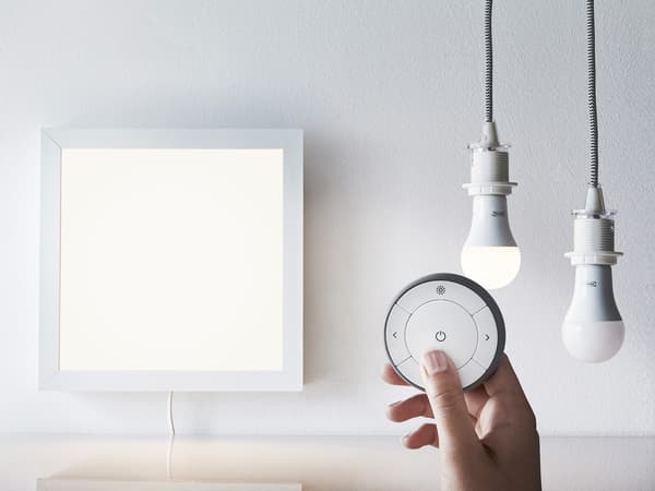 Lien vers 'Guide d’utilisation de l’éclairage intelligent' – photo d’une télécommande intelligente TRÅDFRI, d’un panneau lumineux et de deux ampoules.