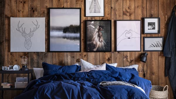 Lien vers « Six conseils pour une décoration murale » - image d’un mur orné de peintures au-dessus d’un lit recouvert de literie bleu roi.