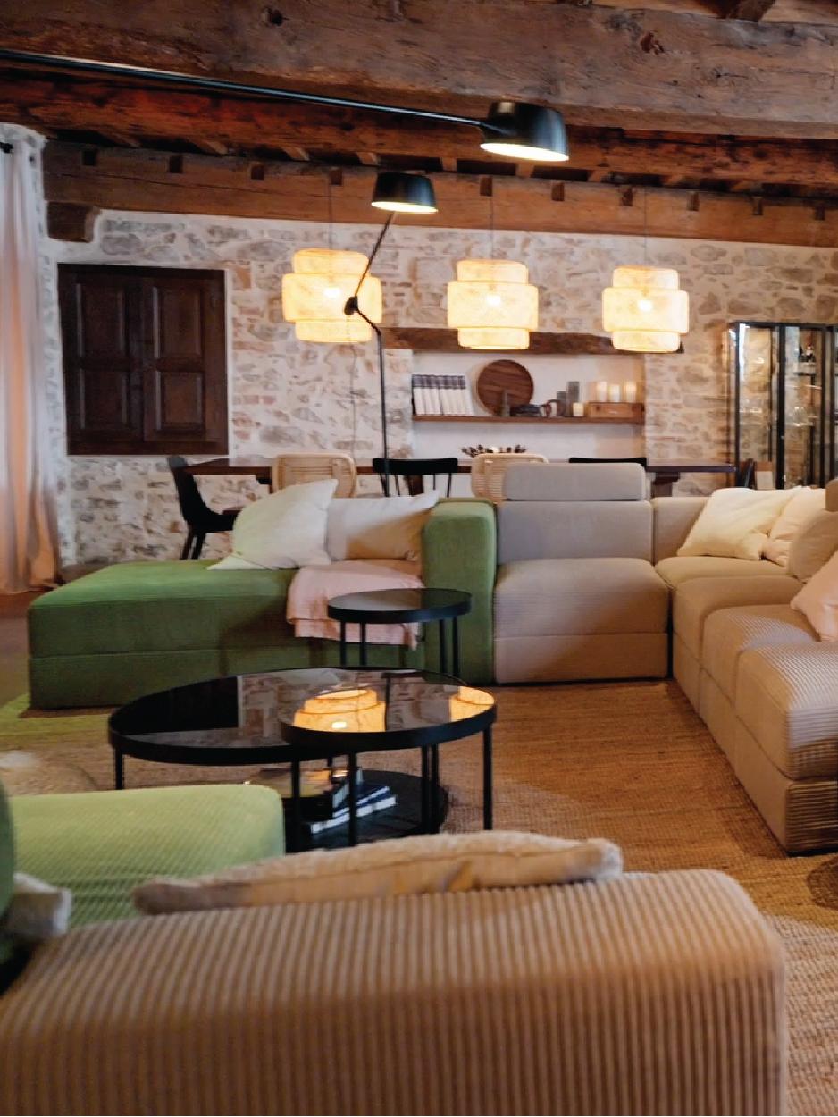 Lieu de vie convivial avec des grands canapés en velour et des poutres apparentes dans un gîte.