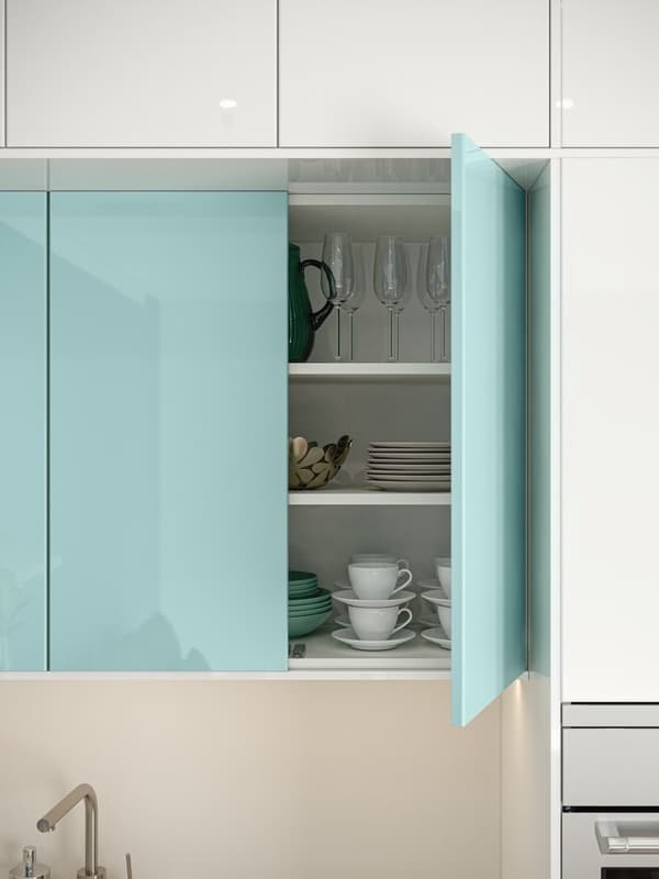 Light blue IKEA tall cabinet with open door on the right side, cups and plates are stowed in the tall cabinet.