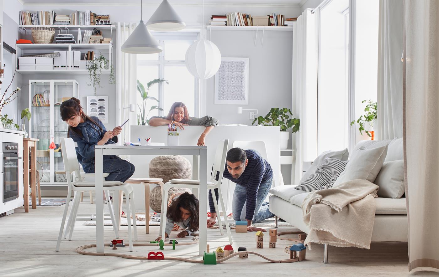 บ้านขนาดกะทัดรัดที่สมาชิกในบ้านเล่นชุดรถไฟ LILLABO/ลิลลาบู อยู่ในห้องที่มีเตียง โซฟา โต๊ะ ครัวขนาดเล็ก และที่เก็บของ