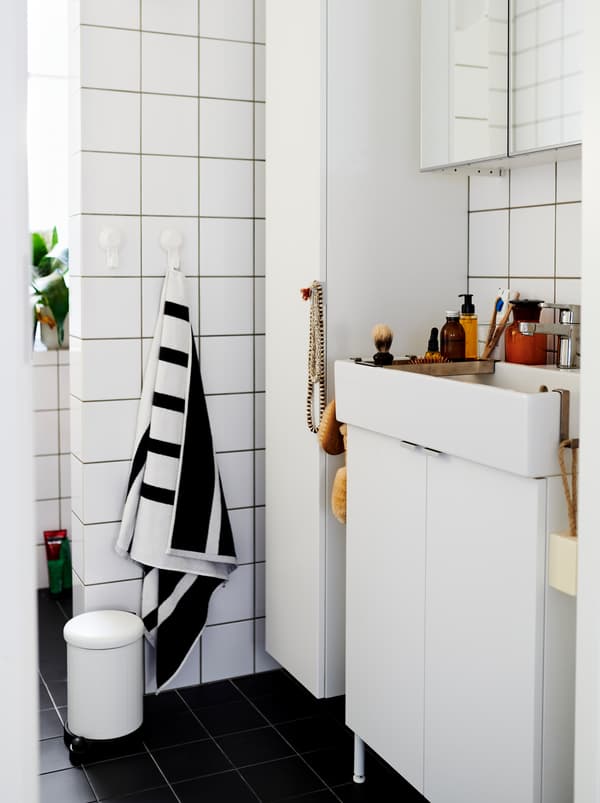 ห้องน้ำที่ปูกระเบื้องสีขาวพร้อมตู้และอ่างล้างหน้า LILLÅNGEN/ลิลลงเง่น สีขาว มีของตกแต่งและเครื่องใช้ในห้องน้ำวางอยู่เต็ม