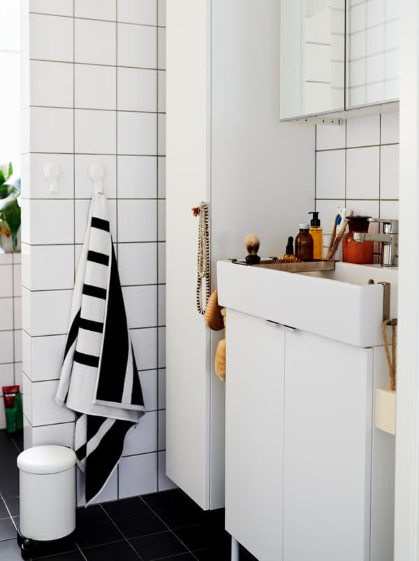 ห้องน้ำที่ปูกระเบื้องสีขาวพร้อมตู้และอ่างล้างหน้า LILLÅNGEN/ลิลลงเง่น สีขาว มีของตกแต่งและเครื่องใช้ในห้องน้ำวางอยู่เต็ม