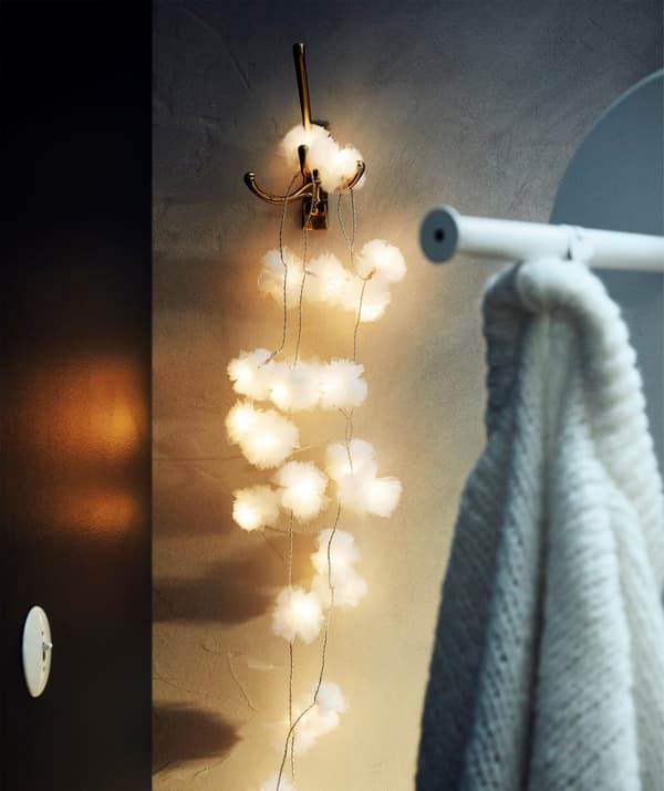 L'illuminazione a LED LIVSÅR con 24 luci su un gancio accanto a un appendiabiti.