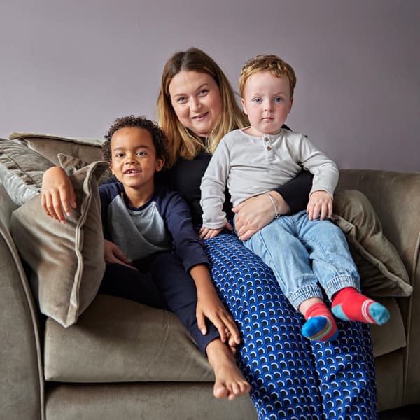 Lily and her two children sitting on a sofa, smiling at the camera.