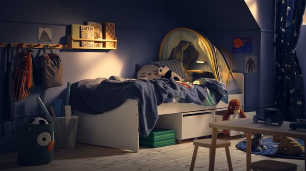 L'image montre une chambre d'enfant avec un lit, des jouets et des boîtes de rangement.