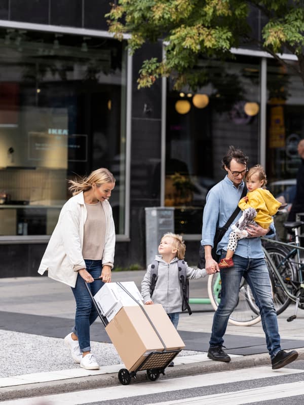 L'image montre une famille de quatre personnes qui sort du magasin avec leurs achats.